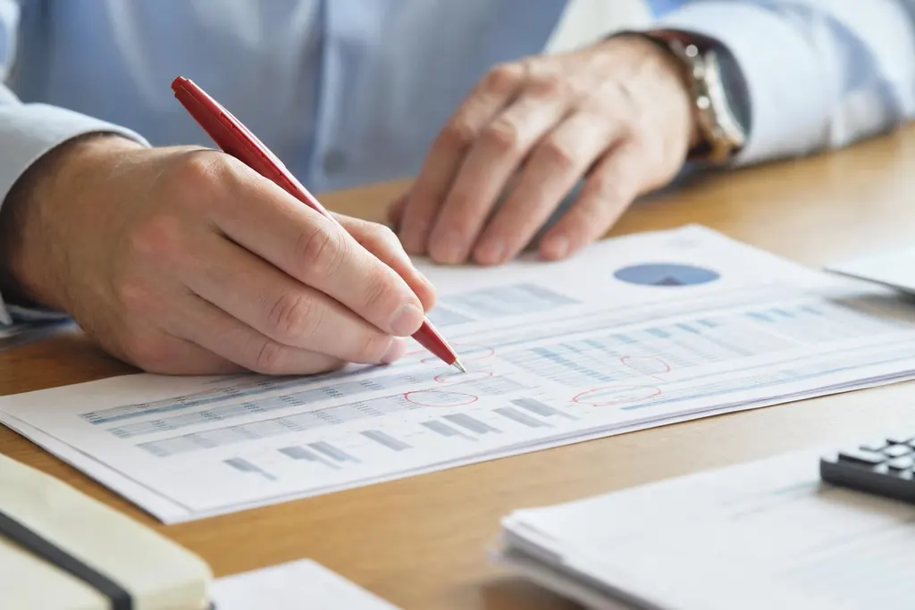 A hand marking up a printed chart page with a red pen